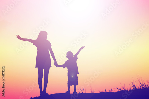 Mother encouraged her son outdoors at sunset, silhouette concept