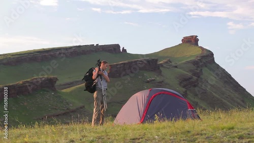 Young woman prepares backpack and walks away from camp photo