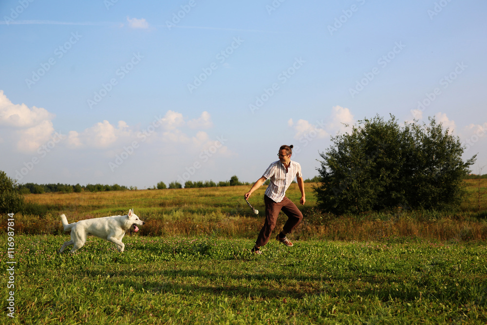 Man playing with white swiss shepherd dog