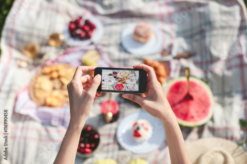 Girl photographing on phone picnic