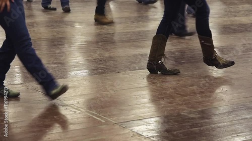 Woman dancing western dance at a country folk festival, wearing cowboy fringed boots and jeans. Music, traditions and fun. Learning line dance
