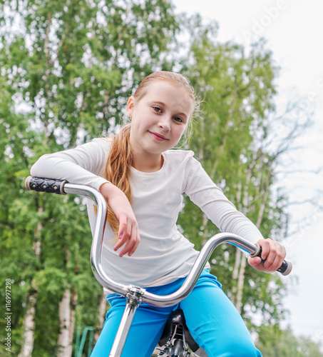 Smiling little girl on a bicycle.