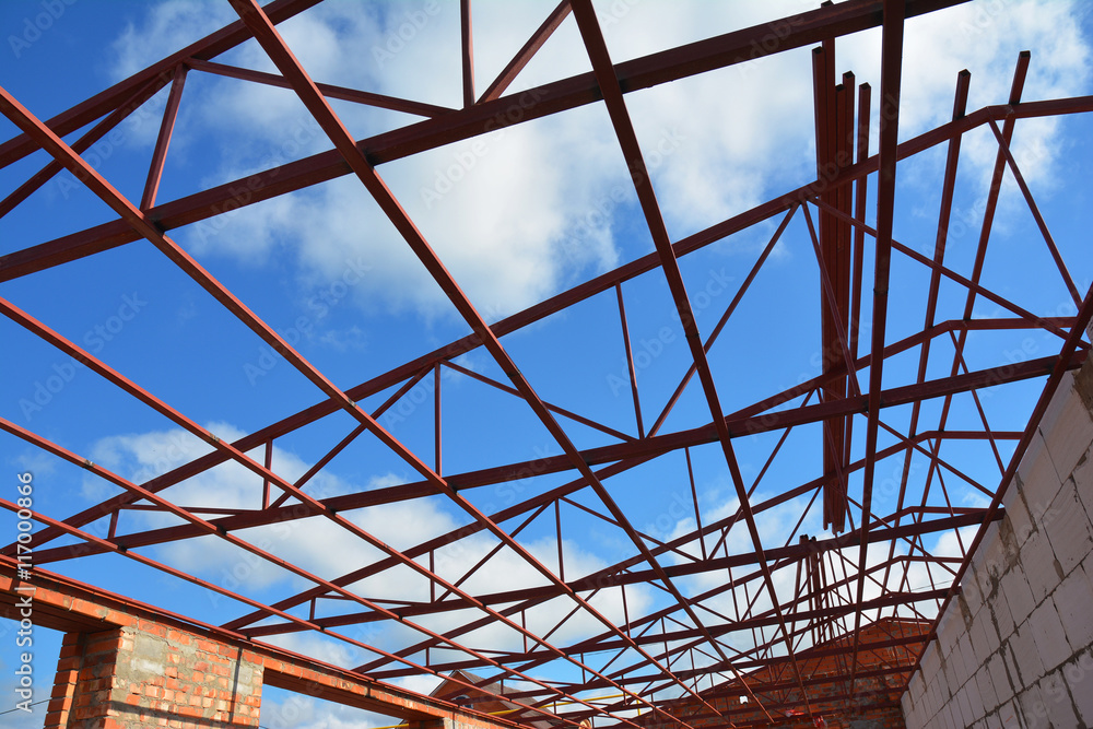 Steel roof trusses details with clouds sky background. Steel roof trusses sitting on concrete pole view from inside home factory. Steel roof trusses details with clouds sky background. Steel roof trusses sitting on concrete pole view from inside home factory.