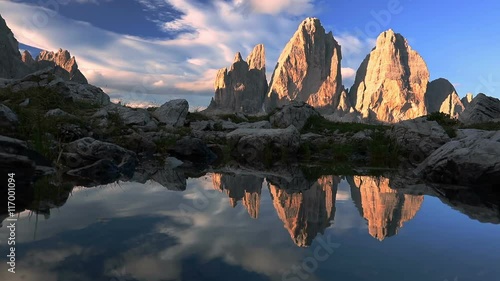 Italy. Dolomites. Early in the morning. The tops of the rocky mountains illuminated by the rising sun and reflected in the mirrored surface of the lake photo