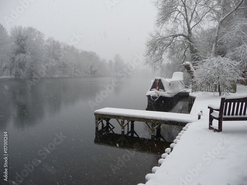 Winter shot of the River Thames near Maidenhead, with snow covering the riverbank, a small jetty and bench in the foreground