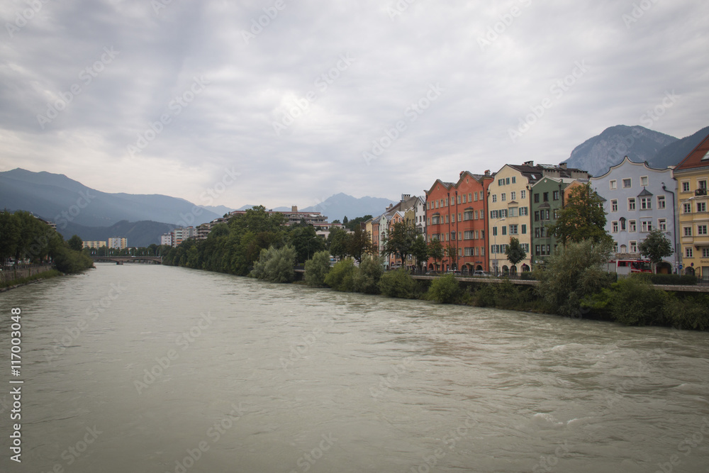 Typical Austrian houses at the embankment of the Inn river in Innsbruck, Austria with the Alps in the background

