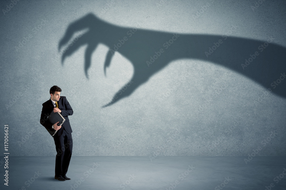 Fototapeta premium Business person afraid of a big monster claw shadow concept
