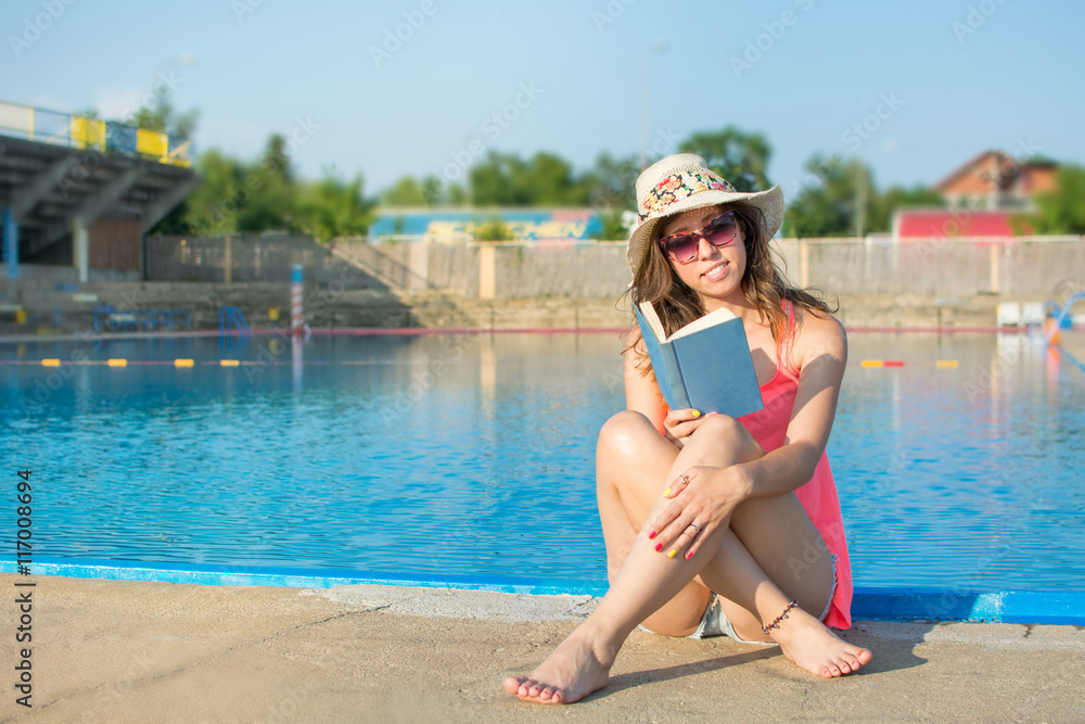 Girl reading a book by the pool.