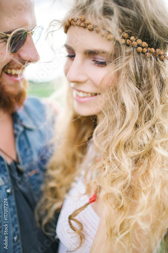 Young hippie male with beard hugging curly female outdoors