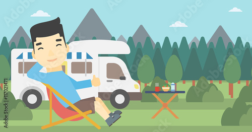 Man sitting in chair in front of camper van.