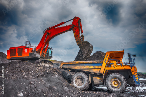 NOVOKUZNETSK, RUSSIA - JULY 26, 2016: Big yellow mining truck and excavator at worksite
