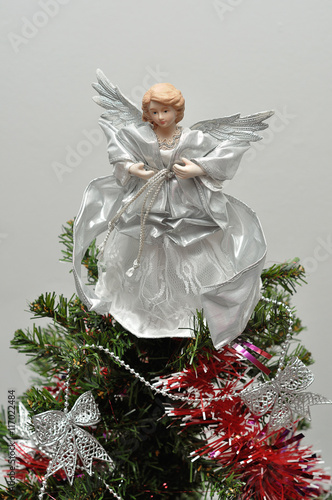 An angel tree topper on top of a Christmas tree