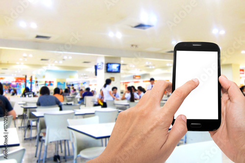 Man use mobile phone, blur image of inside food court background.