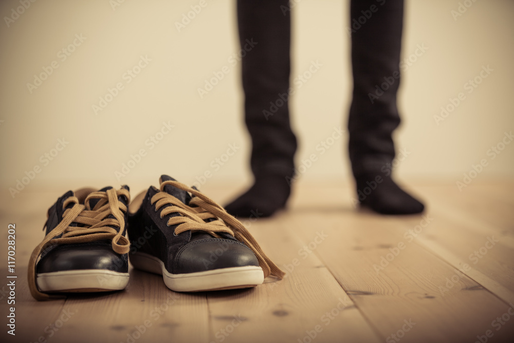 Person Standing Behind Pair of Shoes on Wood Floor Person Standing Behind Pair of Shoes on Wood Floor