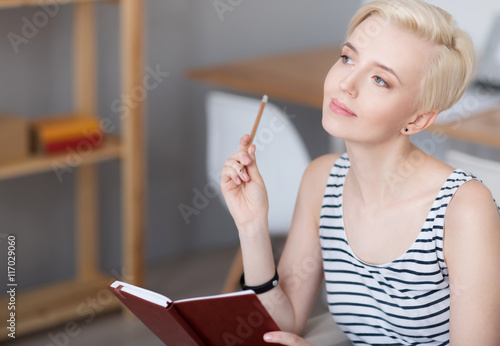 Woman thinking and holding diary