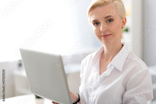 Woman looking at camera and holding laptop