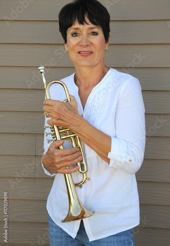 Sticker Female jazz trumpet player holding her horn outside.