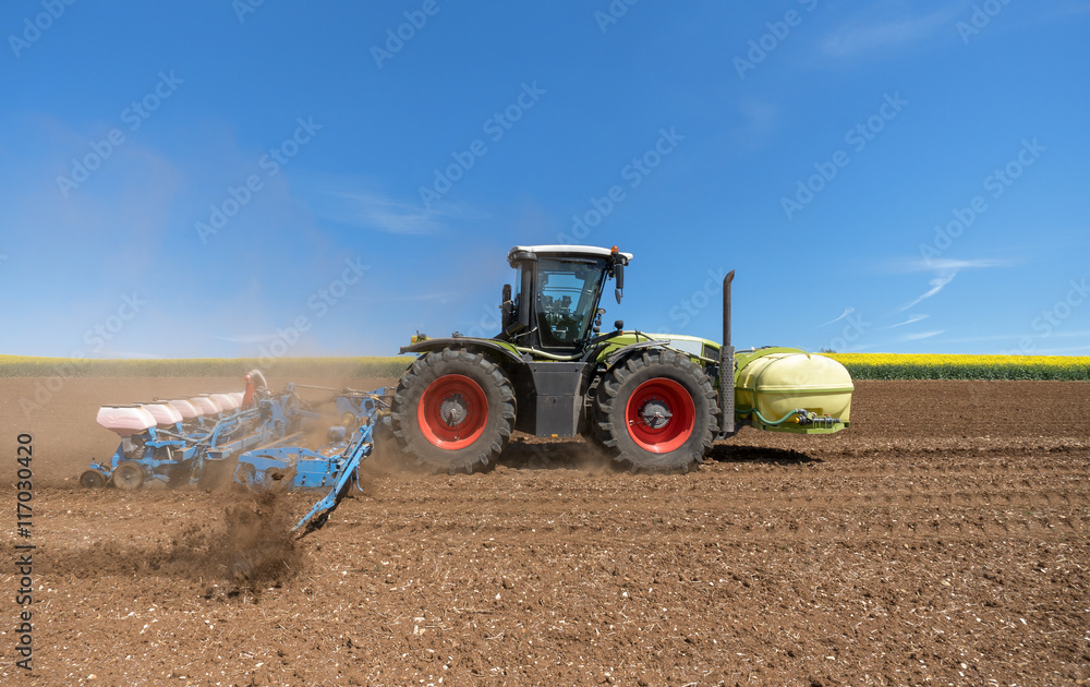 Obraz premium Traktor mit Sämaschine auf einem Feld bei der Arbeit 