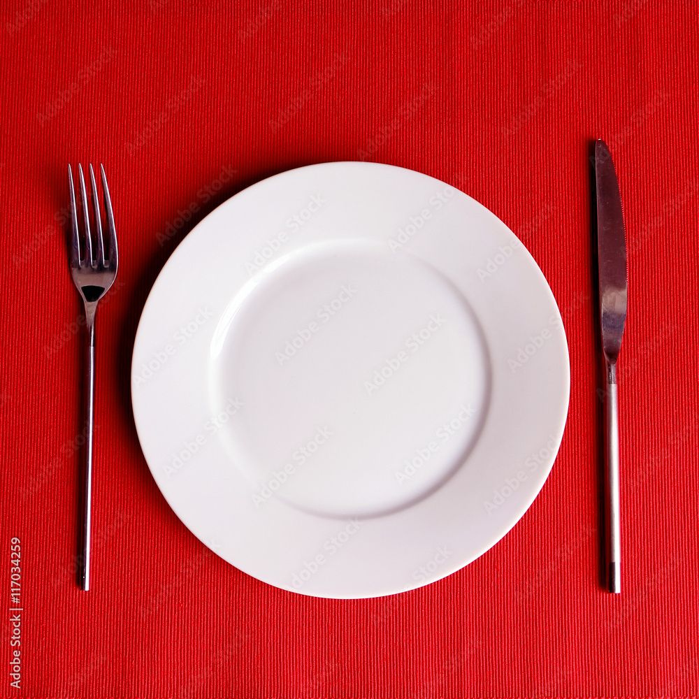 White plate with cutlery on e red backgrouns (napkin) White plate with cutlery on e red backgrouns (napkin)
