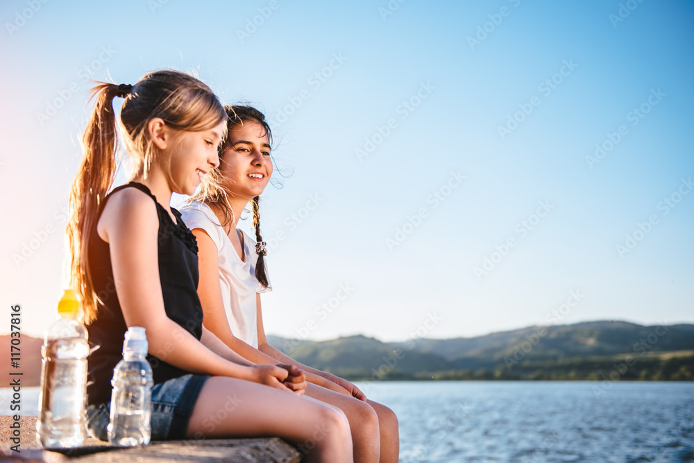 Two girls sitting by the sea and laughing together