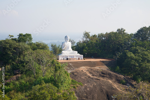 View of the sculpture of sitting Buddha in the morning mist. Mihintale, Sri Lanka photo