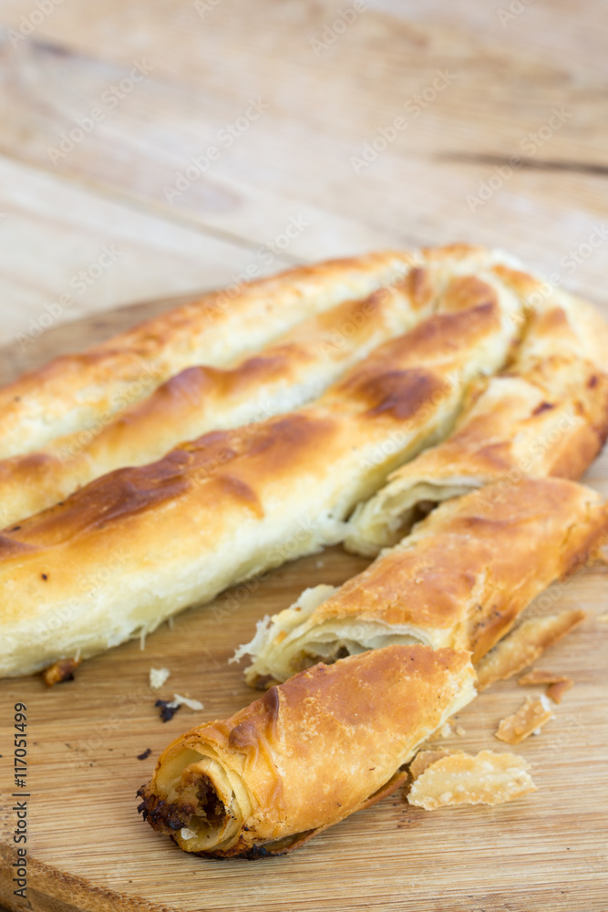 Rustic homemade burek pie with meat on the wooden background Rustic homemade burek pie with meat on the wooden background