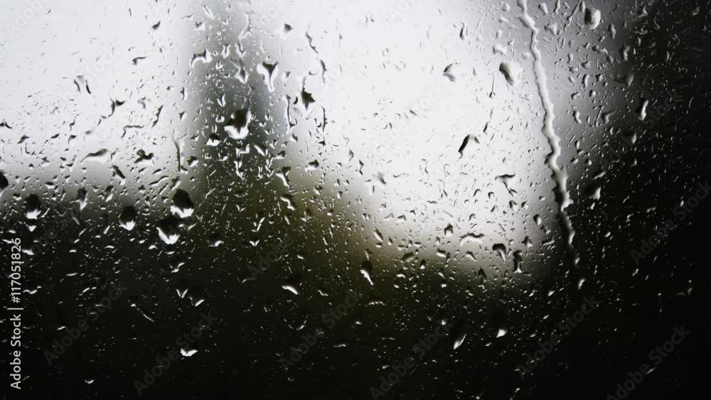 Close-up of water droplets on glass. Rain drops on window glass with blur background. Blurred tree and sky. Rainy days, rain running down window, bokeh Close-up of water droplets on glass. Rain drops on window glass with blur background. Blurred tree and sky. Rainy days, rain running down window, bokeh