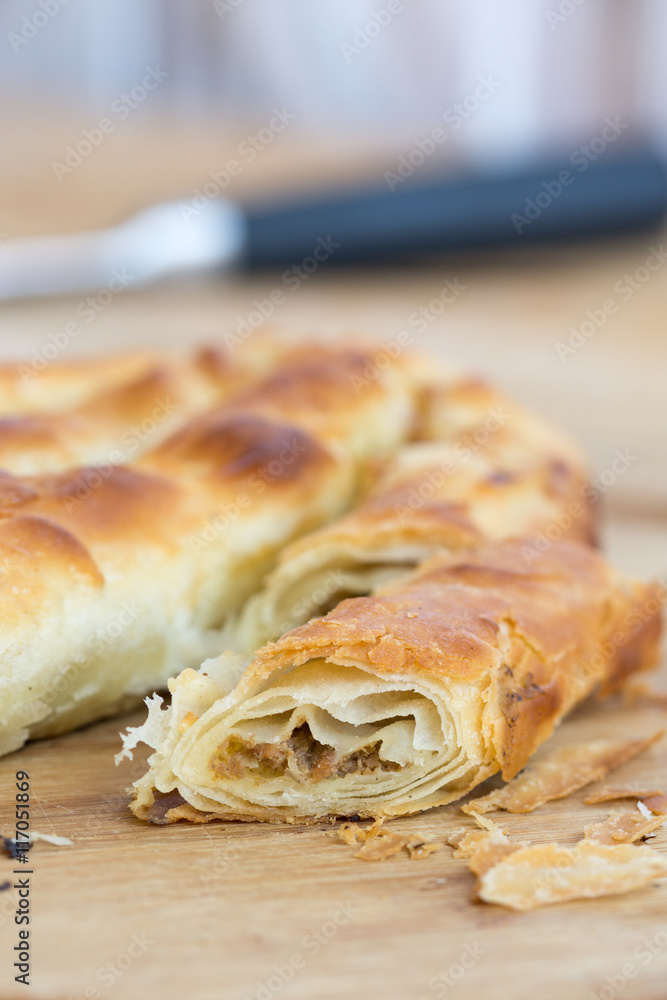 Sliced burek with meat on the wooden board. Rustic food. Sliced burek with meat on the wooden board. Rustic food.