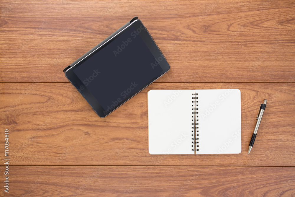 Top view of digital tablet and notebook on wood table Top view of digital tablet and notebook on wood table