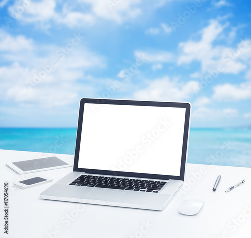 Laptop computer on office table with blur blue sea background © littlestocker