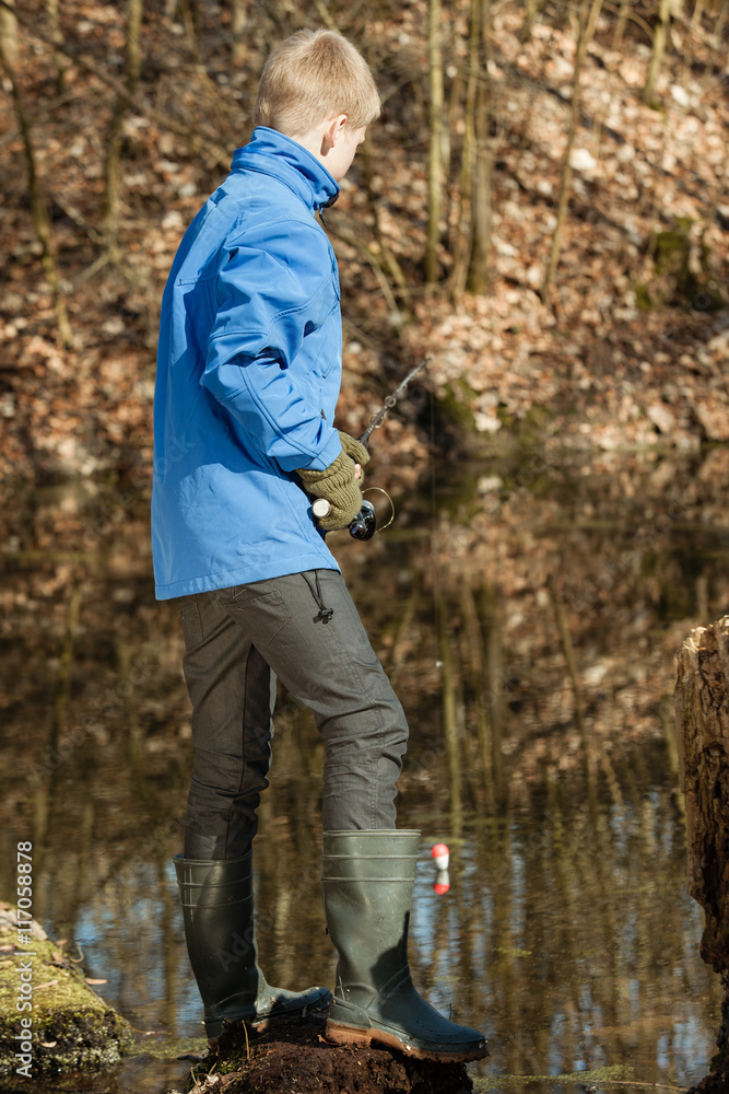Single boy in blue jacket at pond fishing alone