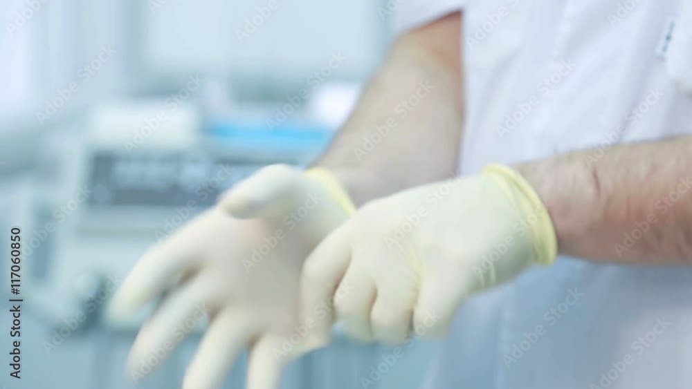 Doctor is a man put on a disposable white gloves closeup. Doctor is a man put on a disposable white gloves closeup.