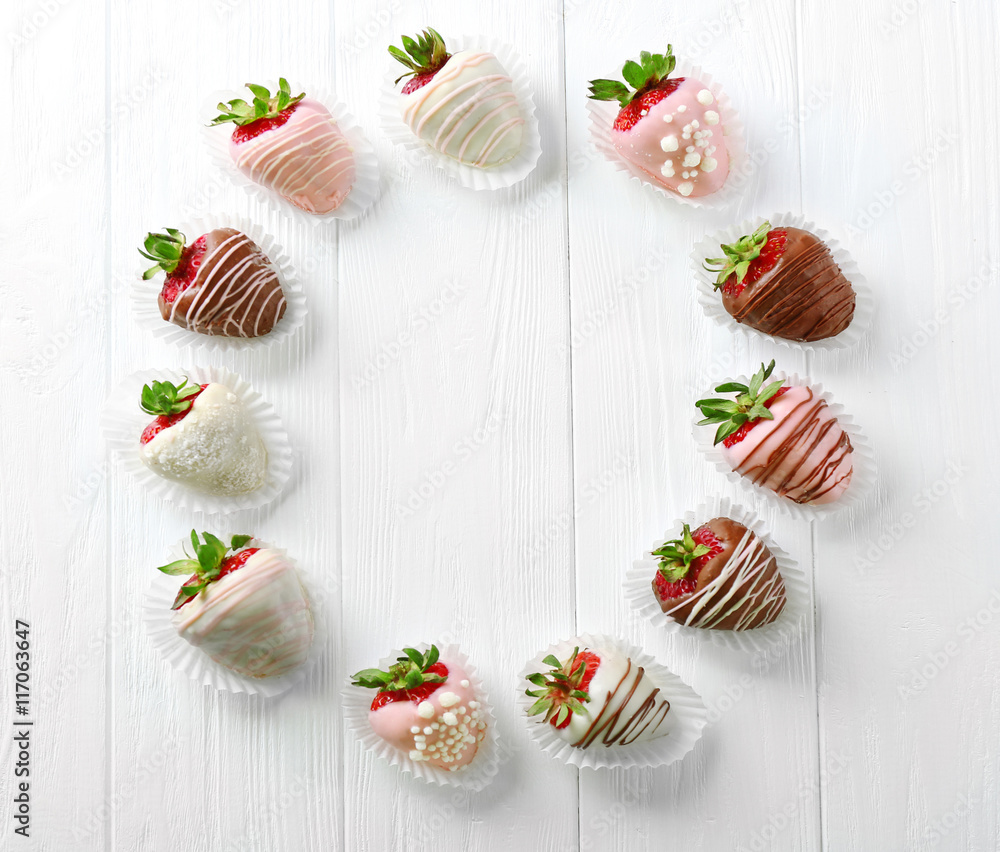 Fototapeta premium Circle of strawberries in chocolate on light wooden background