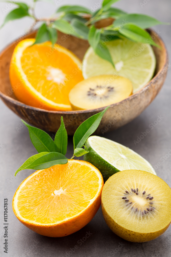 Mixed citrus fruit lemons, orange, kiwi, limes on a gray backgro Mixed citrus fruit lemons, orange, kiwi, limes on a gray backgro