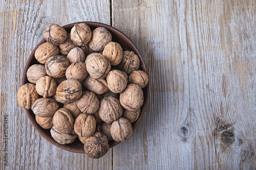 walnuts in a clay plate on a wooden background. top view