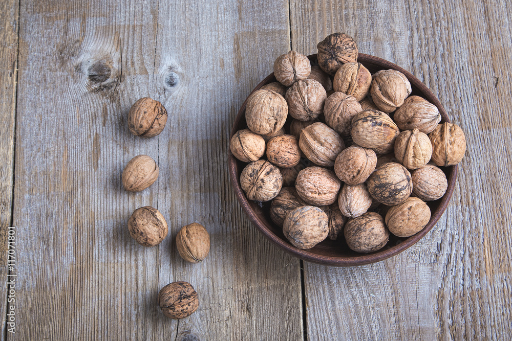 walnuts in a clay plate on a wooden background. top view walnuts in a clay plate on a wooden background. top view