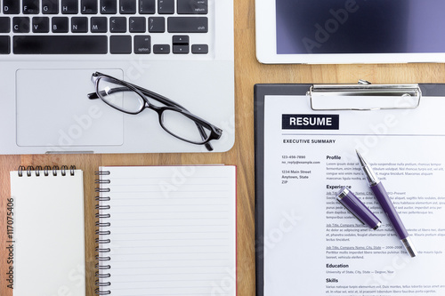Businessman or HR Manager review a resume on his desk with Magnifier, computer laptop, digital tablet, calculator and glasses. Resume information with magnifier. Flat lay.