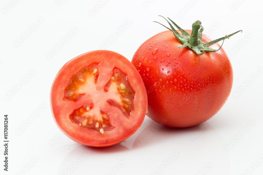 One whole tomato and one sliced tomato on a white background.