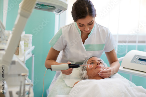 woman in cosmetic hat receiving darsonvalization facial treatmen