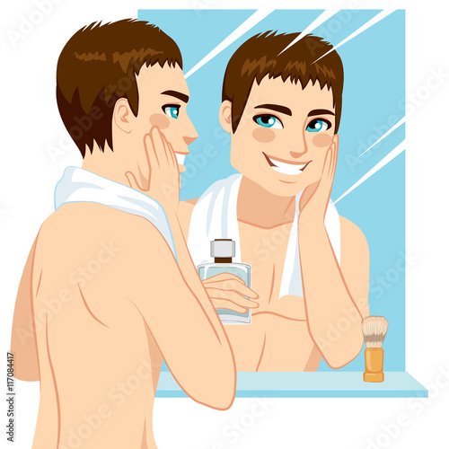 Handsome man applying after shave in his face in front of mirror