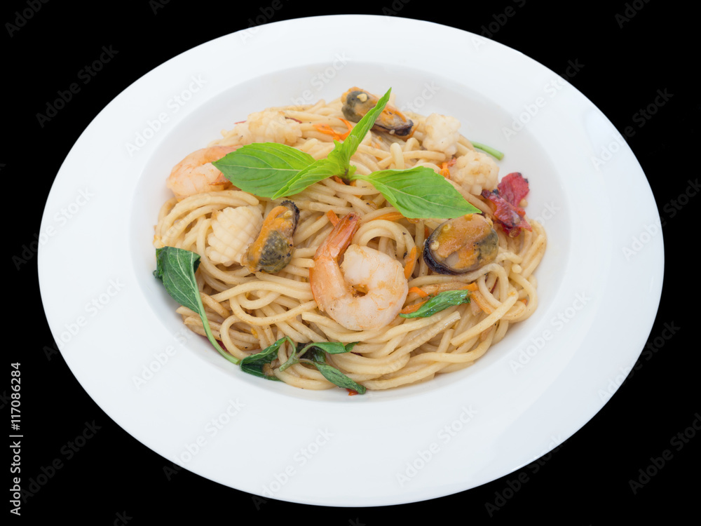 Spaghetti spicy with seafood on a white plate isolated on the black background with clipping path Spaghetti spicy with seafood on a white plate isolated on the black background with clipping path