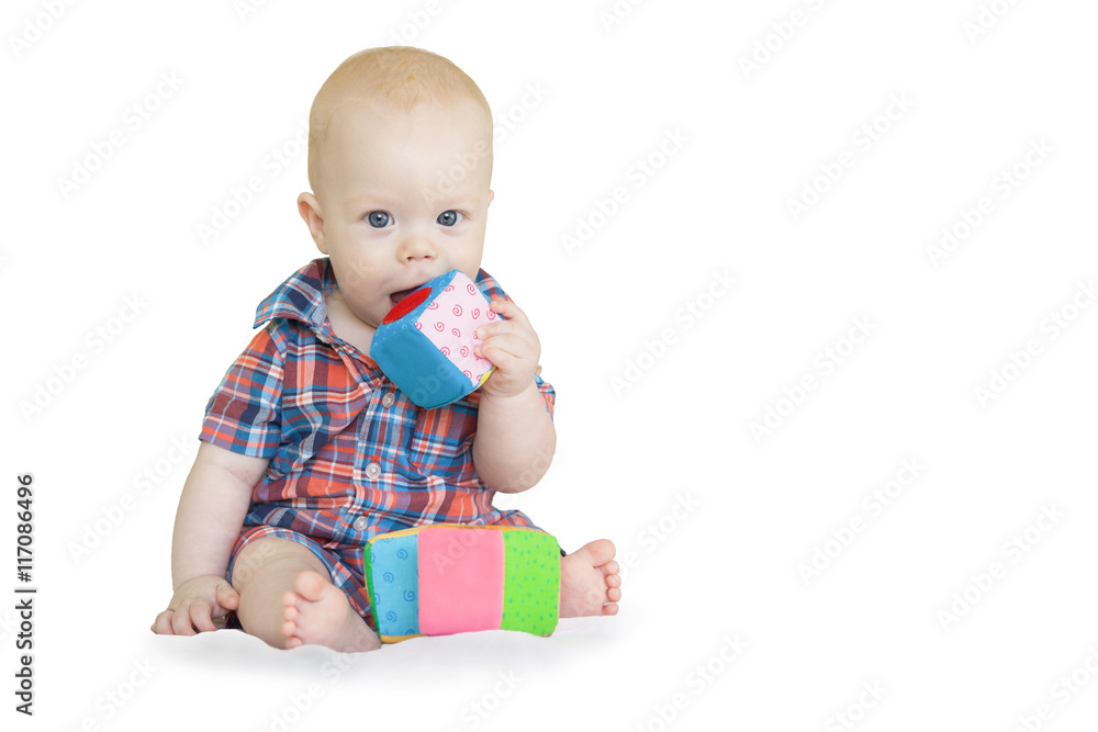 Baby boy in checkered shirt sits and plays with multi-colored soft cubes