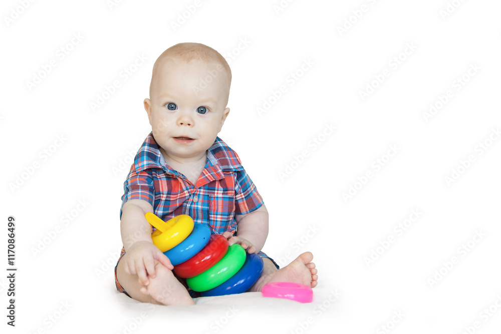 Baby boy in checkered shirt sits and plays with multi-colored pyramid