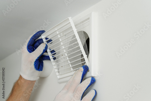 Worker installs ventilation grille. photo