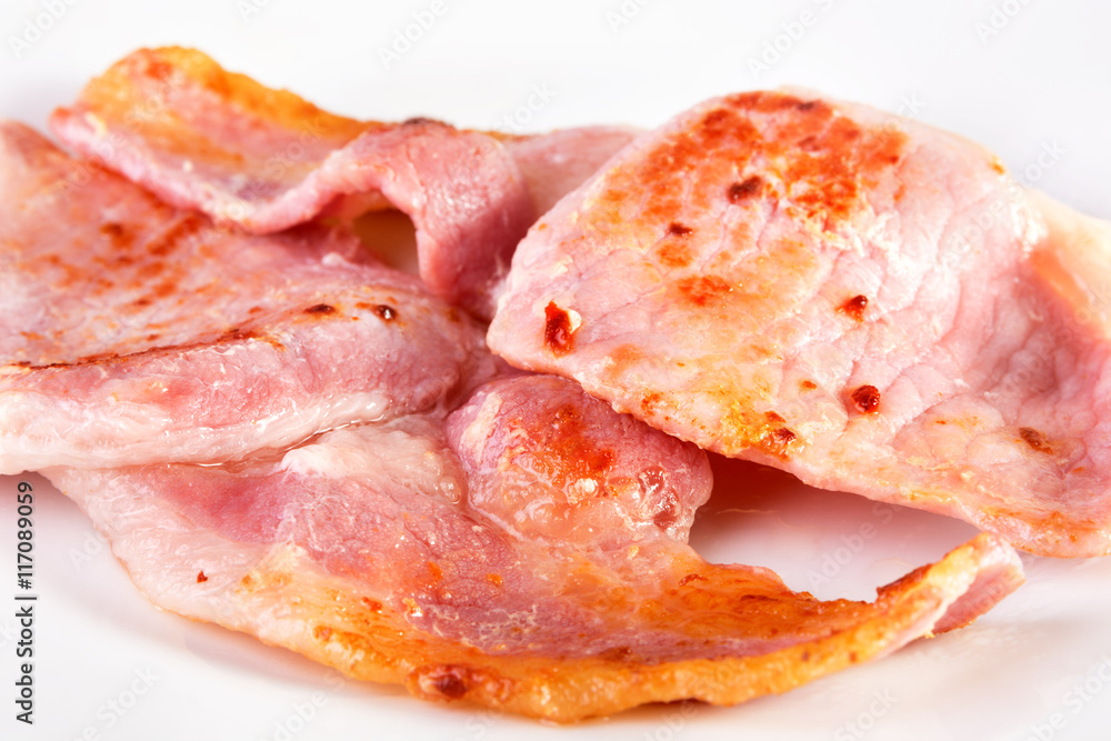 Fried bacon slices on a white plate. SDOF Fried bacon slices on a white plate. SDOF