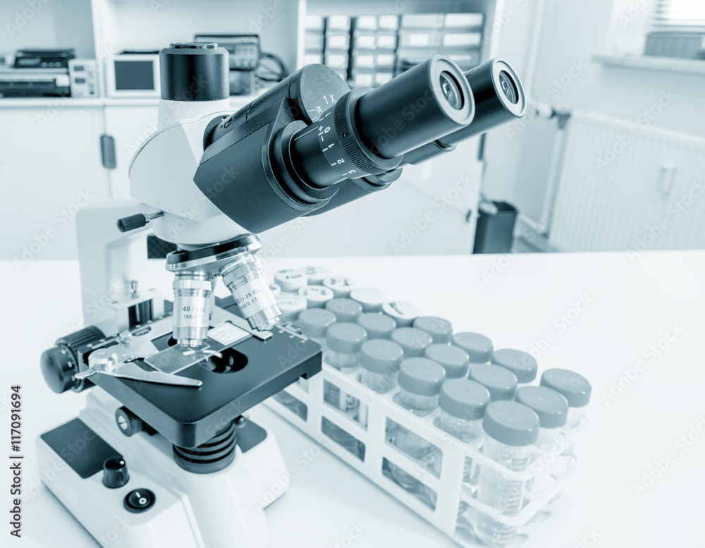 Science microscope on lab bench. Microbiology laboratory. Blue toned image of binocular microscope. Water sampling procedure for microbiological analysis Science microscope on lab bench. Microbiology laboratory. Blue toned image of binocular microscope. Water sampling procedure for microbiological analysis