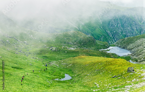 Group of hikers passing through a foggy valley in the Carpathian