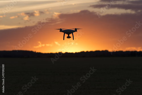 Drone silhouetted against orange sunset