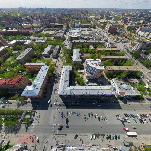 Aerial city view with crossroads and roads, houses, buildings, parks and parking lots, bridges. Copter shot. Panoramic image.