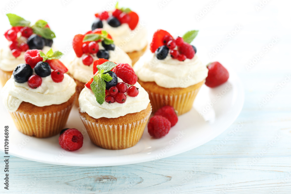 Tasty cupcakes with berries on white wooden table Tasty cupcakes with berries on white wooden table